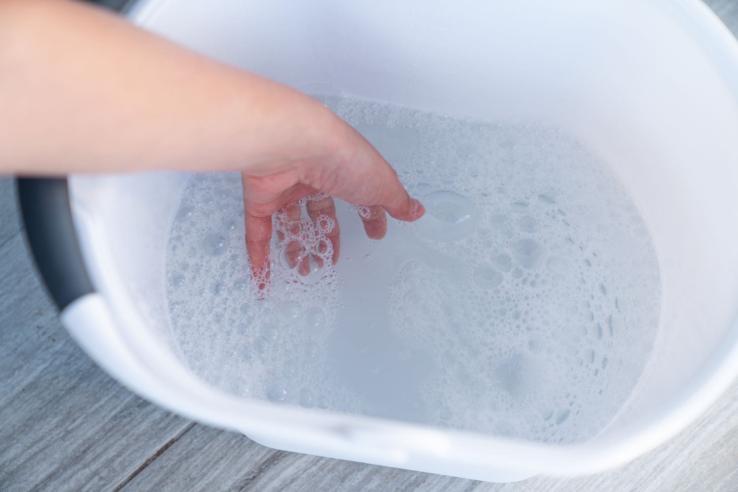 A container filled with water combined with dish soap for a cleaning mixture.