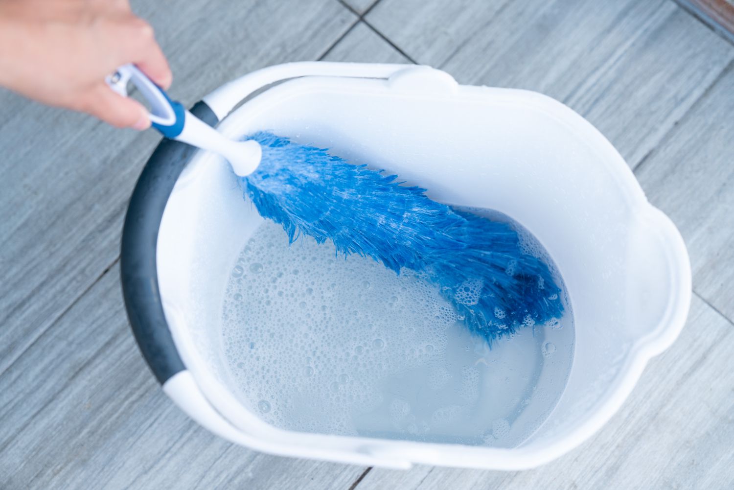 An electrostatic duster cleaned in a bucket filled with water and dish soap.