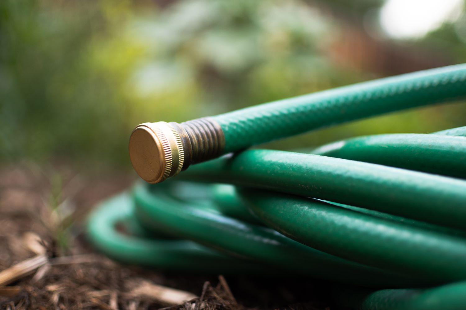 Close-up of a green garden hose with a cap firmly attached to its end.