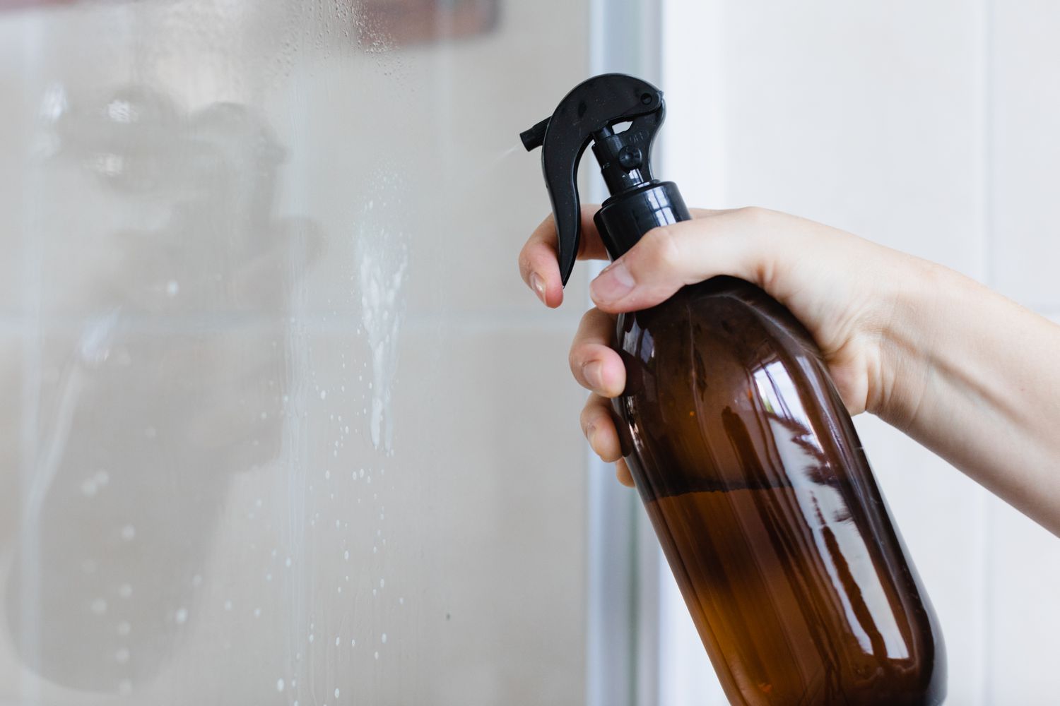 Applying a cleaning agent to the surfaces of the shower doors.