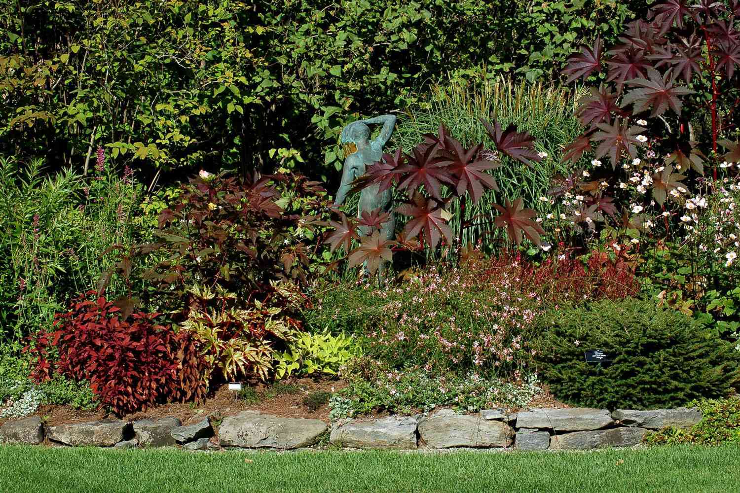 A diverse arrangement featuring a combination of shrubs, perennial flowers, annual blooms, and tropical vegetation.